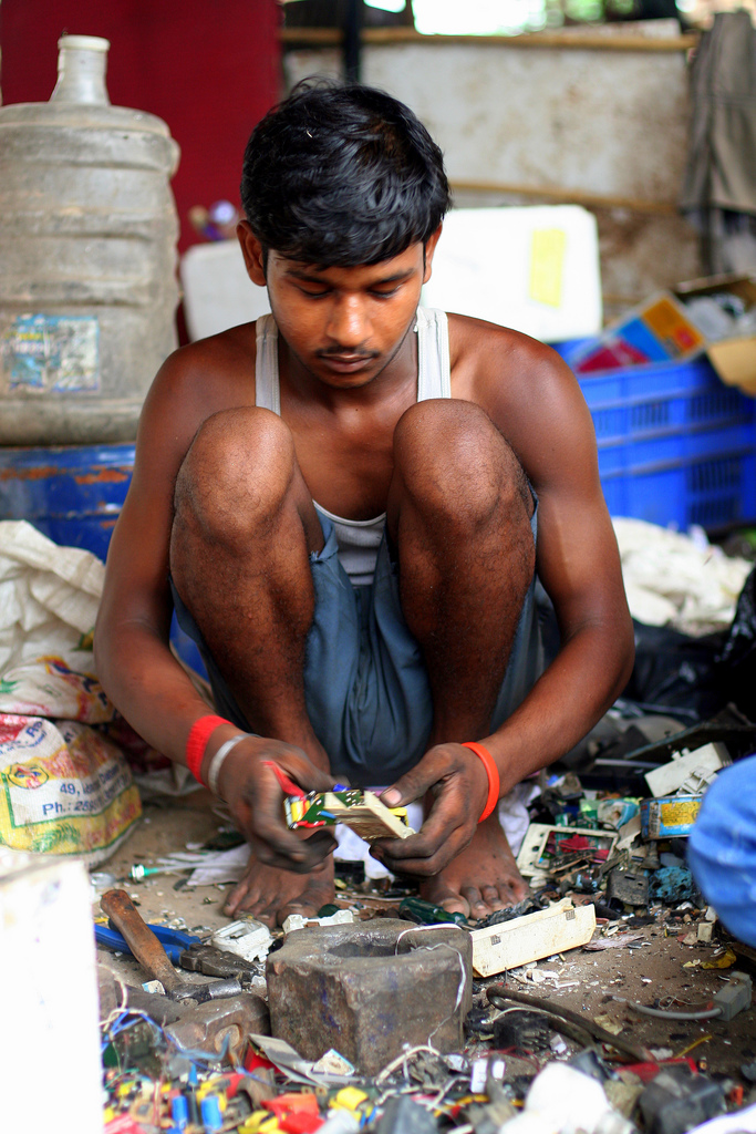 A man removes metal from circuit boards